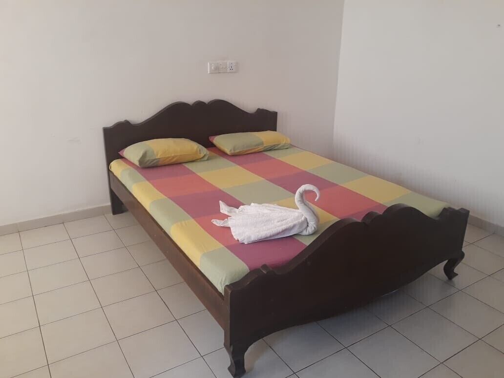 Una cama individual con una colcha a cuadros, dos almohadas y una toalla con forma de cisne.