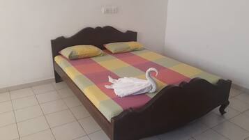 Una cama individual con una colcha a cuadros, dos almohadas y una toalla con forma de cisne.