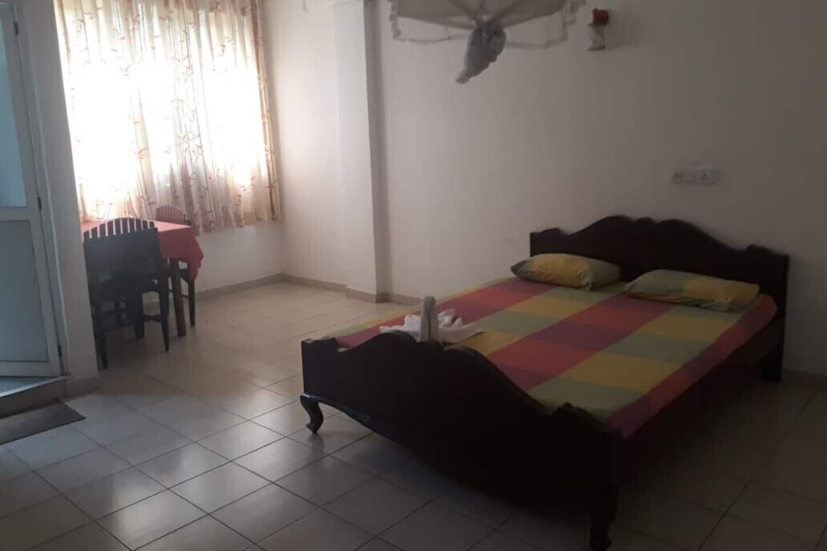 Un dormitorio con cama, una silla y una ventana con cortinas.