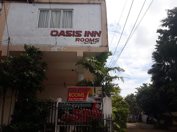 Un bâtiment sur lequel on peut lire l’enseigne « Oasis Inn Rooms ».