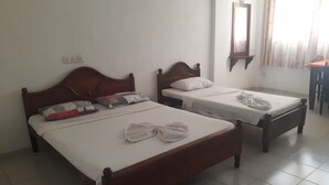 Two wooden beds with white linens and towels, a mirror on the wall, and a tiled floor. - Oasis Inn (Negombo)