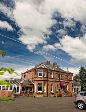 A historic building with a corner entrance, large windows, and a red awning. - Somerton House Hotel (Lockerbie)