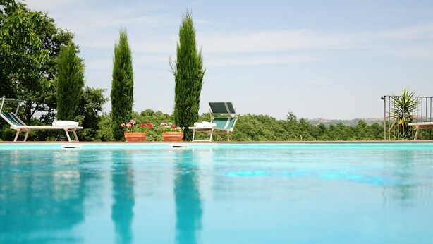 A swimming pool with lounge chairs and potted plants. - Agriturismo Chieteno (Cetona)