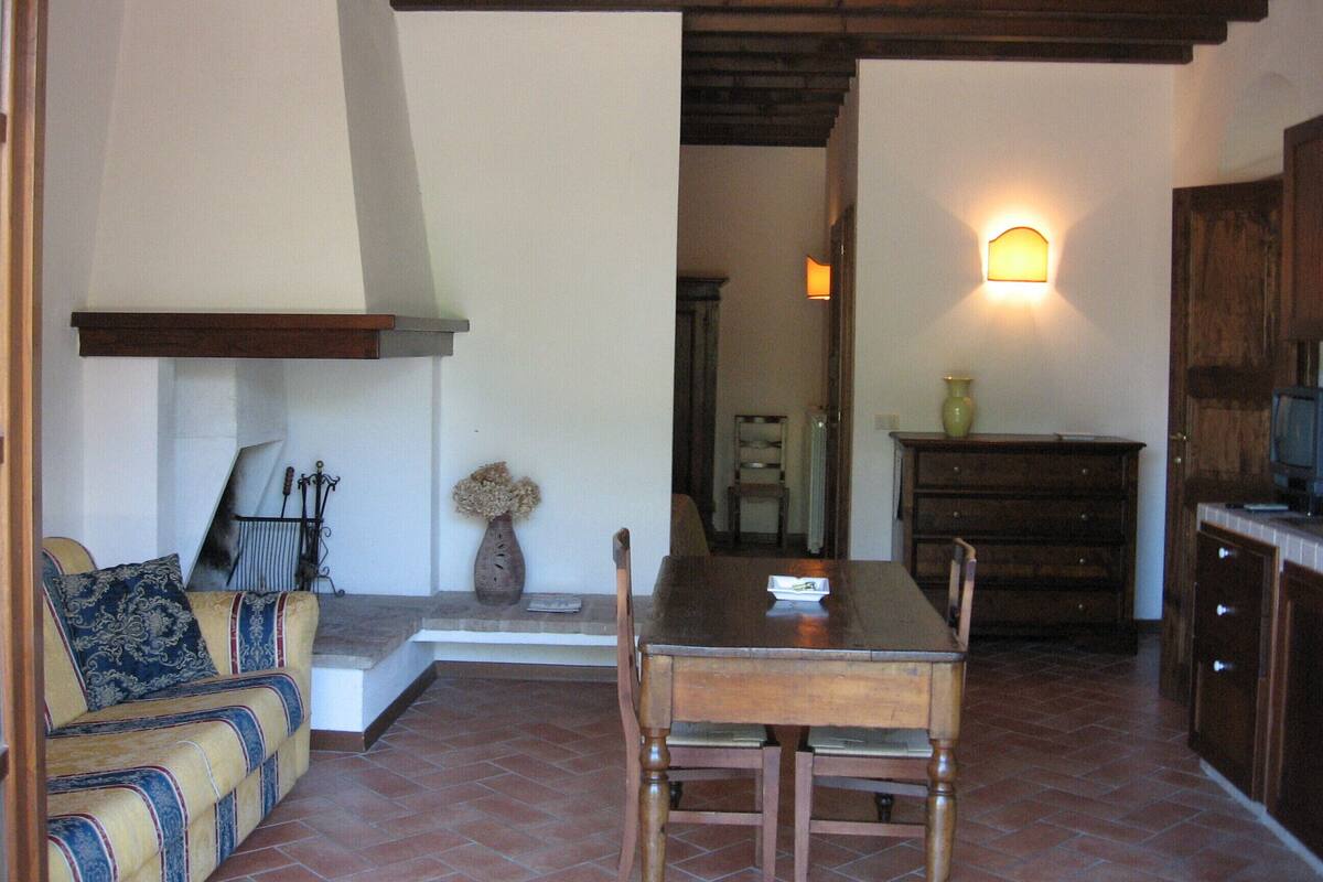 A cozy living area with a sofa, a dining table, and a kitchen area with cabinets and a television.