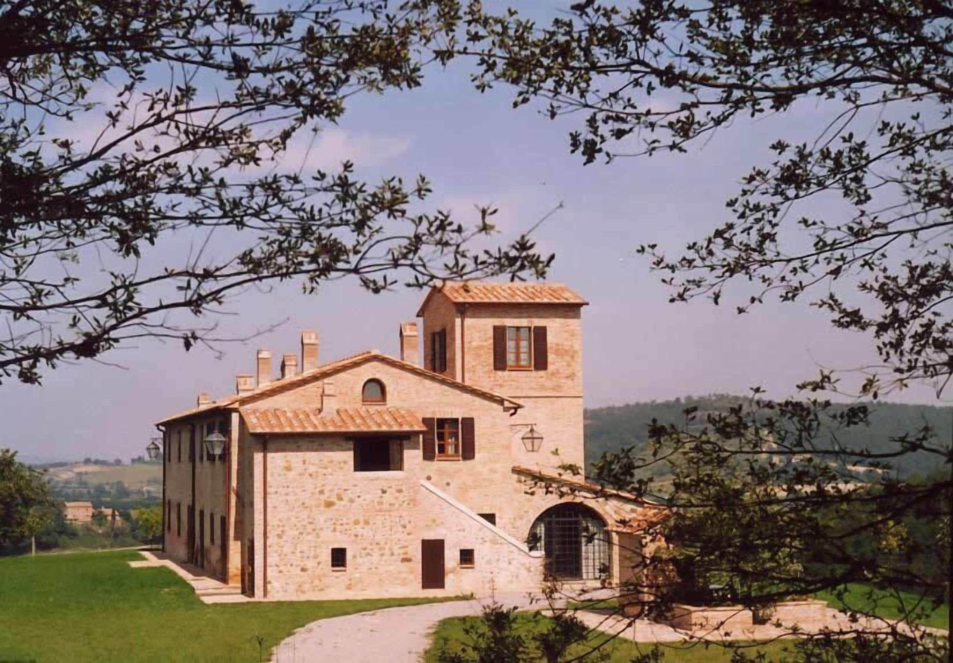Un edificio in pietra con una torre, una scala e un portone.