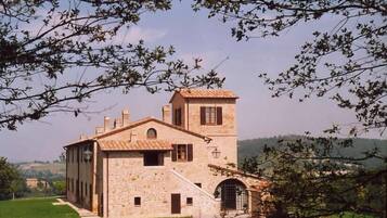 Un edificio in pietra con una torre, una scala e un portone.