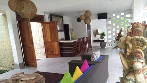 A modern living area with a sofa, a wooden sculpture, and a dining area with chairs and a table. - Adi Abian Villas (Pecatu)