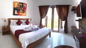 A hotel room with a large bed, a wooden nightstand, a bedside table, a TV, and a desk with a chair. - Adi Abian Villas (Pecatu)