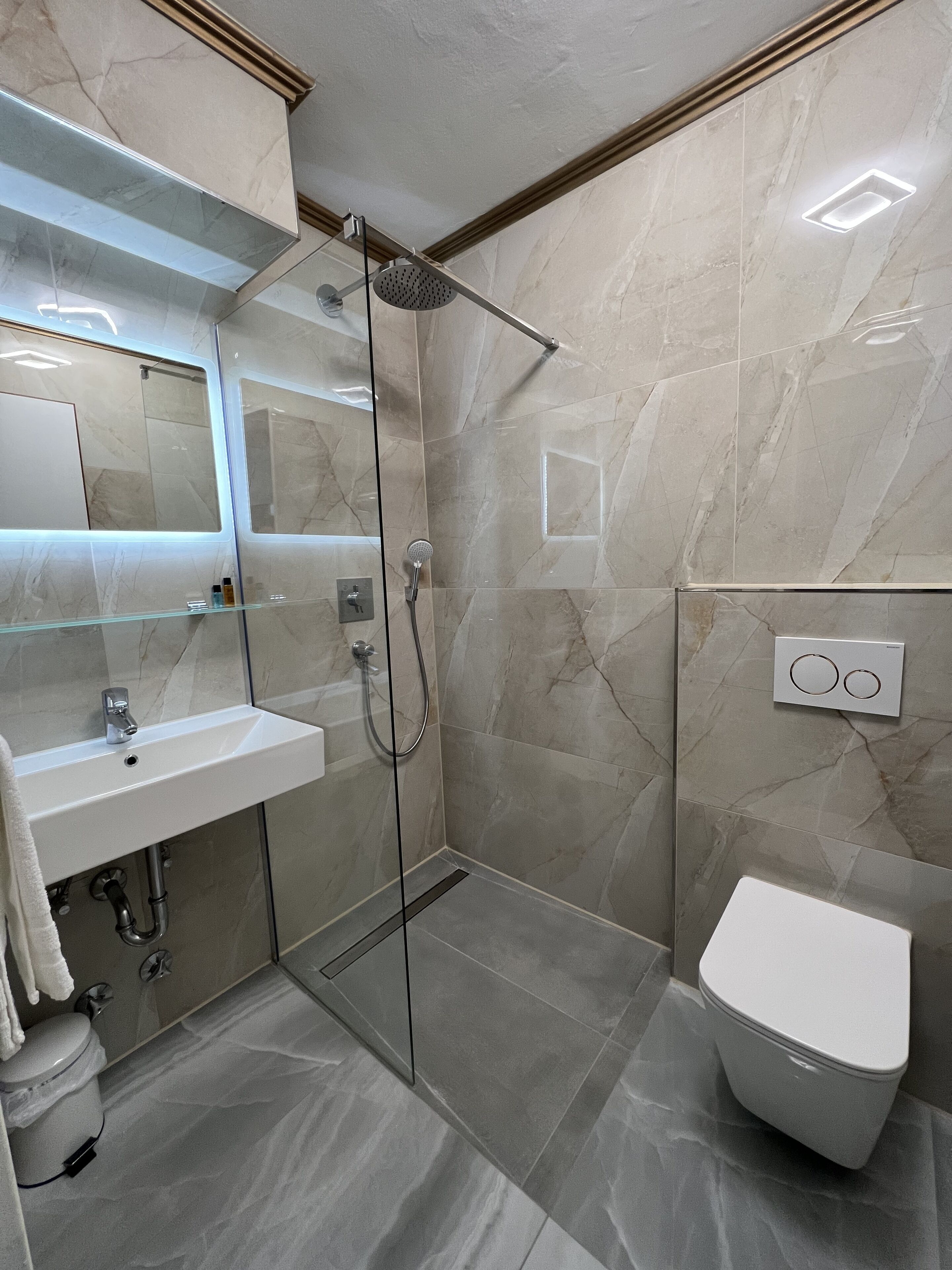 A modern bathroom with a glass-enclosed shower, a white sink, and a toilet.