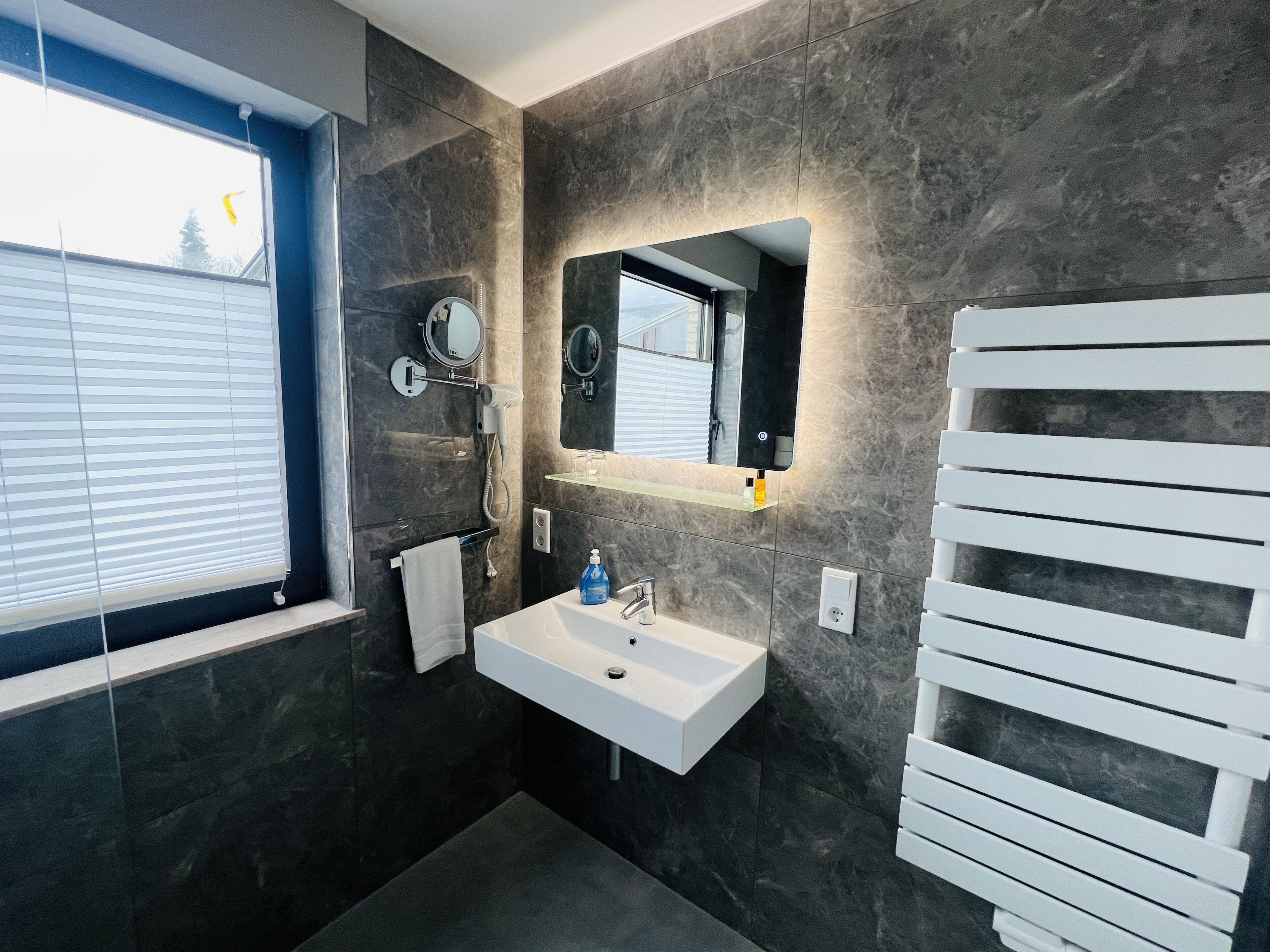 A modern bathroom with a white sink, a mirror, and a towel rack.