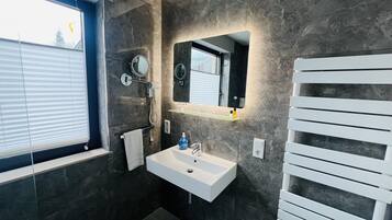 A modern bathroom with a white sink, a mirror, and a towel rack.