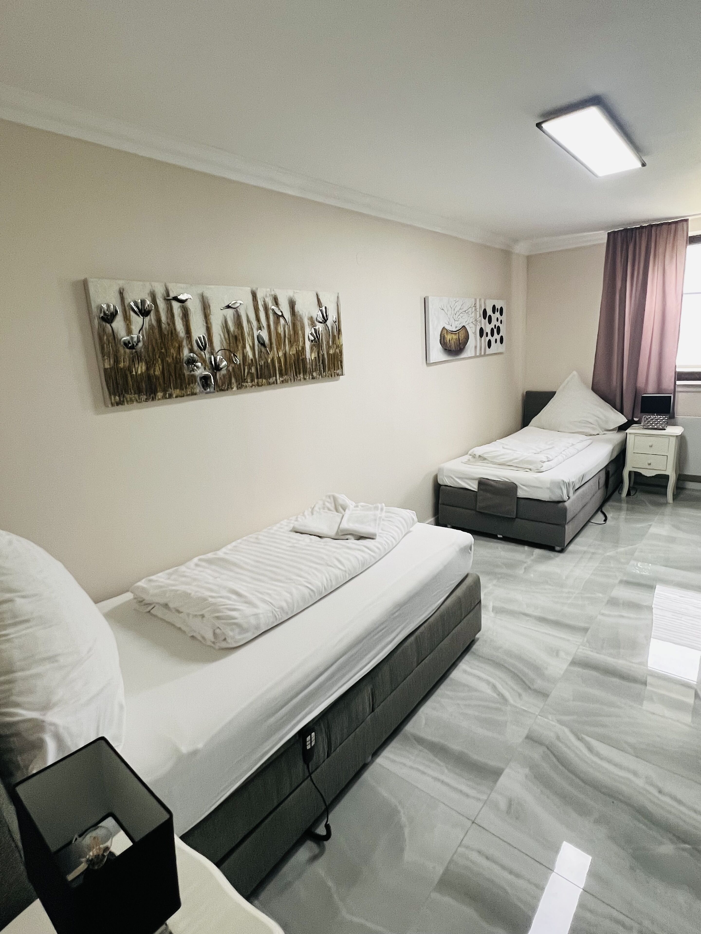 Een hotelkamer met een bed, een bureau en een stoel. Twee schilderijen hangen aan de muur.