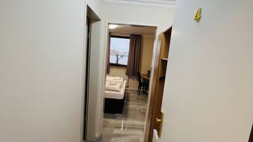 Un pasillo de hotel con piso de mármol, una cama al fondo y una puerta con el número 4.