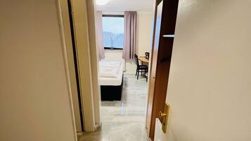 Un pasillo de hotel con una cama, un escritorio y vista al mar.