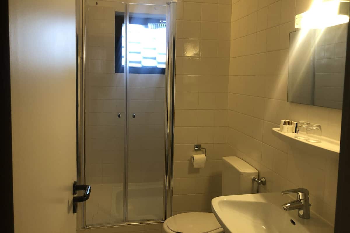 Une salle de bain avec une douche à parois de verre, des toilettes, un lavabo avec un miroir au-dessus et un porte-serviettes.