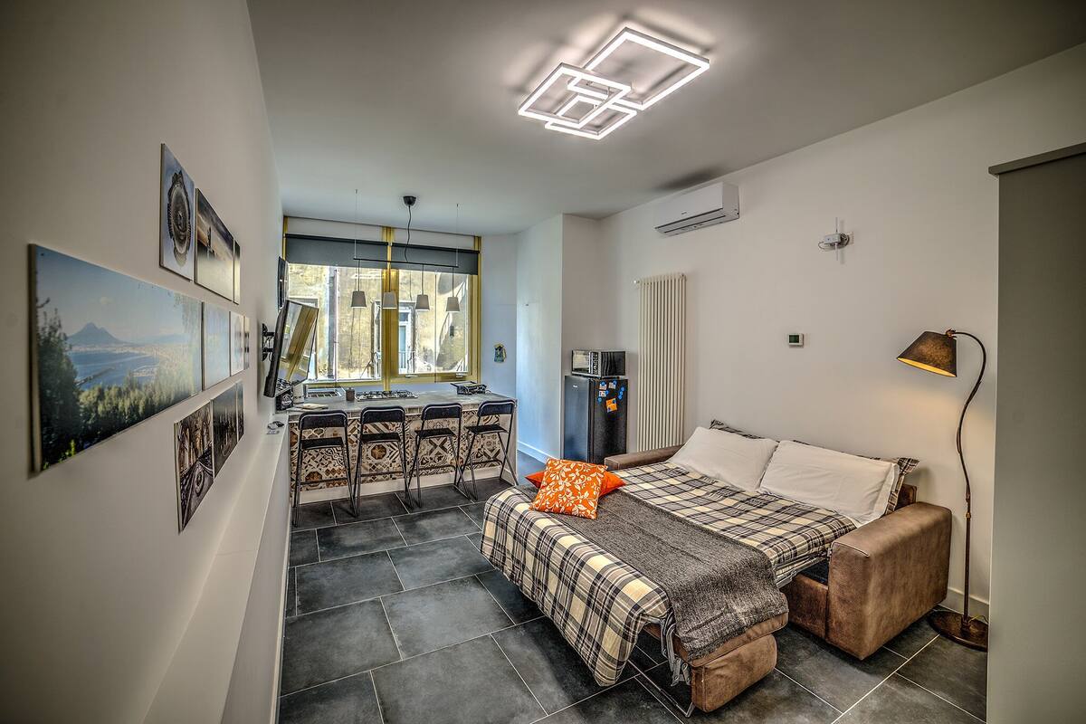 A compact hotel room with a bed, a desk, and a kitchenette.