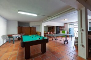 A recreational room with a pool table, foosball table, and ping pong table.
