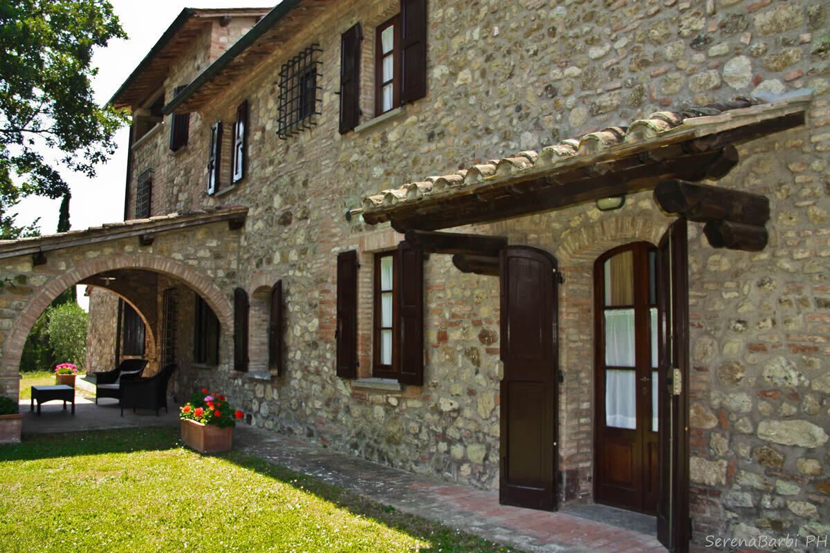 Un edificio in pietra con un cortile interno, con una panchina di legno e piante in vaso.
