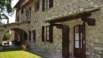 Un edificio in pietra con un cortile interno, con una panchina di legno e piante in vaso.