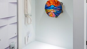 Un intérieur blanc avec un téléphone, un objet en verre aux couleurs vives et un objet rouge posé sur le dessus.