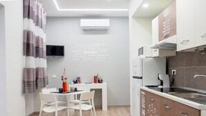Une cuisine moderne avec des meubles blancs, un four encastré et un four  à micro-ondes. On y trouve également un coin repas avec une table et des chaises blanches.