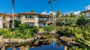 A resort with a pool surrounded by tropical plants and palm trees.