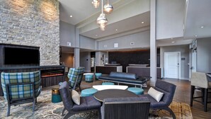 A spacious living area with a stone wall, a flat-screen TV, comfortable seating, and a modern chandelier. - Residence Inn by Marriott Middletown Goshen (Middletown)