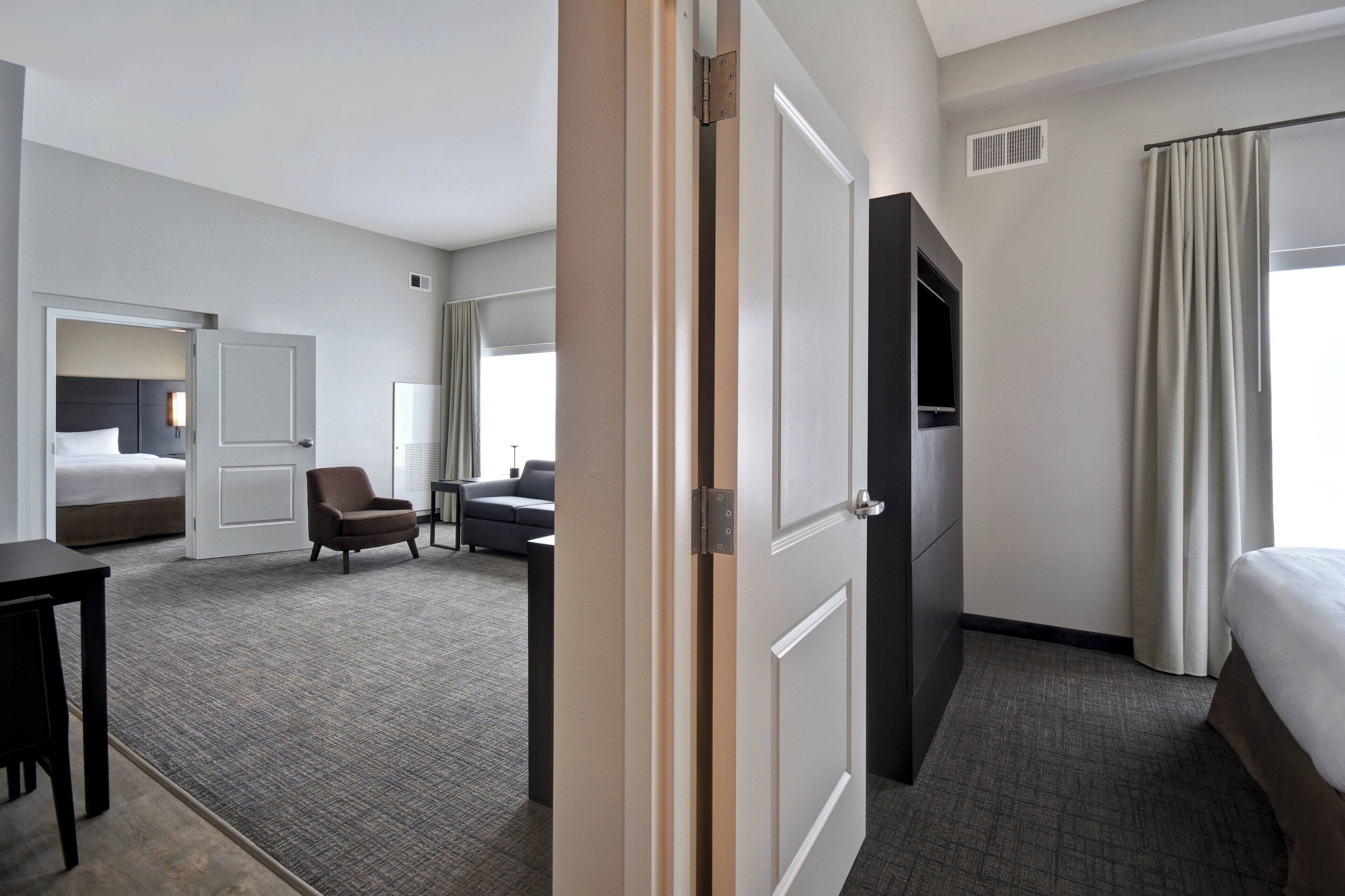 A hotel room with a bed, a desk, a chair, a television, and a window with curtains.