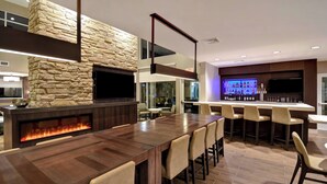A modern bar area with a stone accent wall, a long wooden bar counter, and a flat-screen TV mounted above the bar. - Residence Inn by Marriott Middletown Goshen (Middletown)