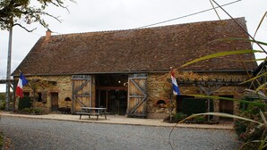 A stone building with a tiled roof, two large wooden doors, and a bench outside. - Domaine Bonneblond - Tentes Glamping (Saint-Désiré)