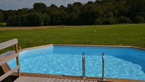 A rectangular swimming pool with a wooden deck and metal handrails, surrounded by a grassy field and trees. - Domaine Bonneblond - Tentes Glamping (Saint-Désiré)