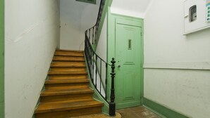 A staircase with wooden steps and black balusters leading to a green door. - C&O Guest House Alcântara-Lisbon (Lisbon)