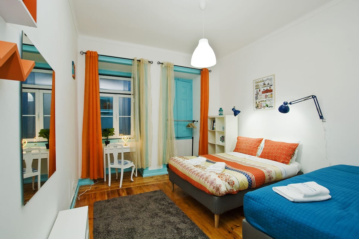 Un dormitorio con cama, mesita de noche, lámpara y escritorio con silla.