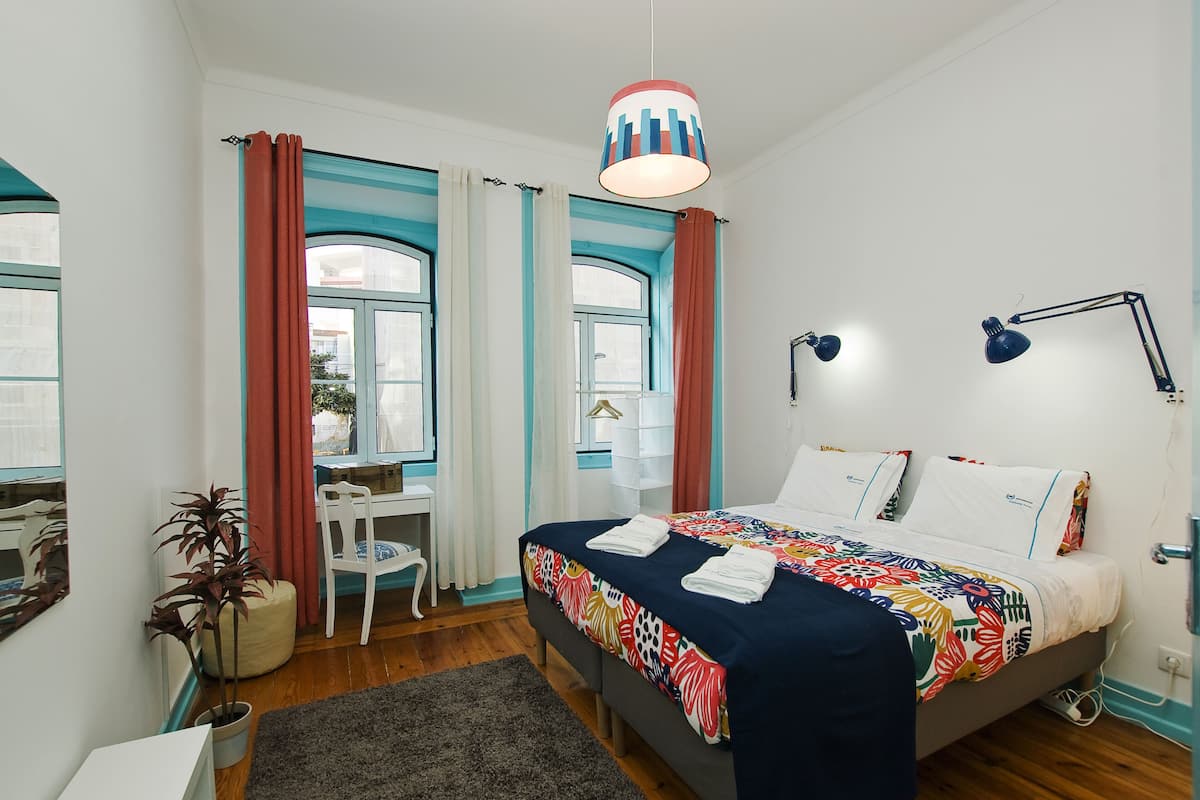 Un dormitorio moderno con cama, lámparas de noche, un escritorio y una silla.