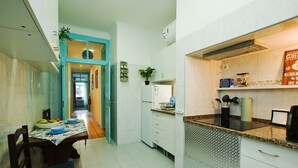 A modern kitchen with white cabinets, a granite countertop, and a dining area with a table set for four. - C&O Guest House Alcântara-Lisbon (Lisbon)