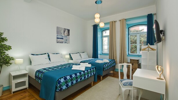A bedroom with two beds, a desk, a chair, a TV, and a window with curtains. - C&O Guest House Alcântara-Lisbon (Lisbon)