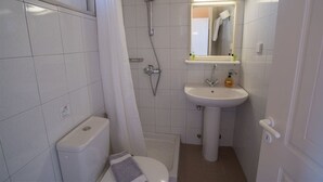A compact bathroom with a toilet, shower, and sink. - Christina Hotel Petriti (Corfu)