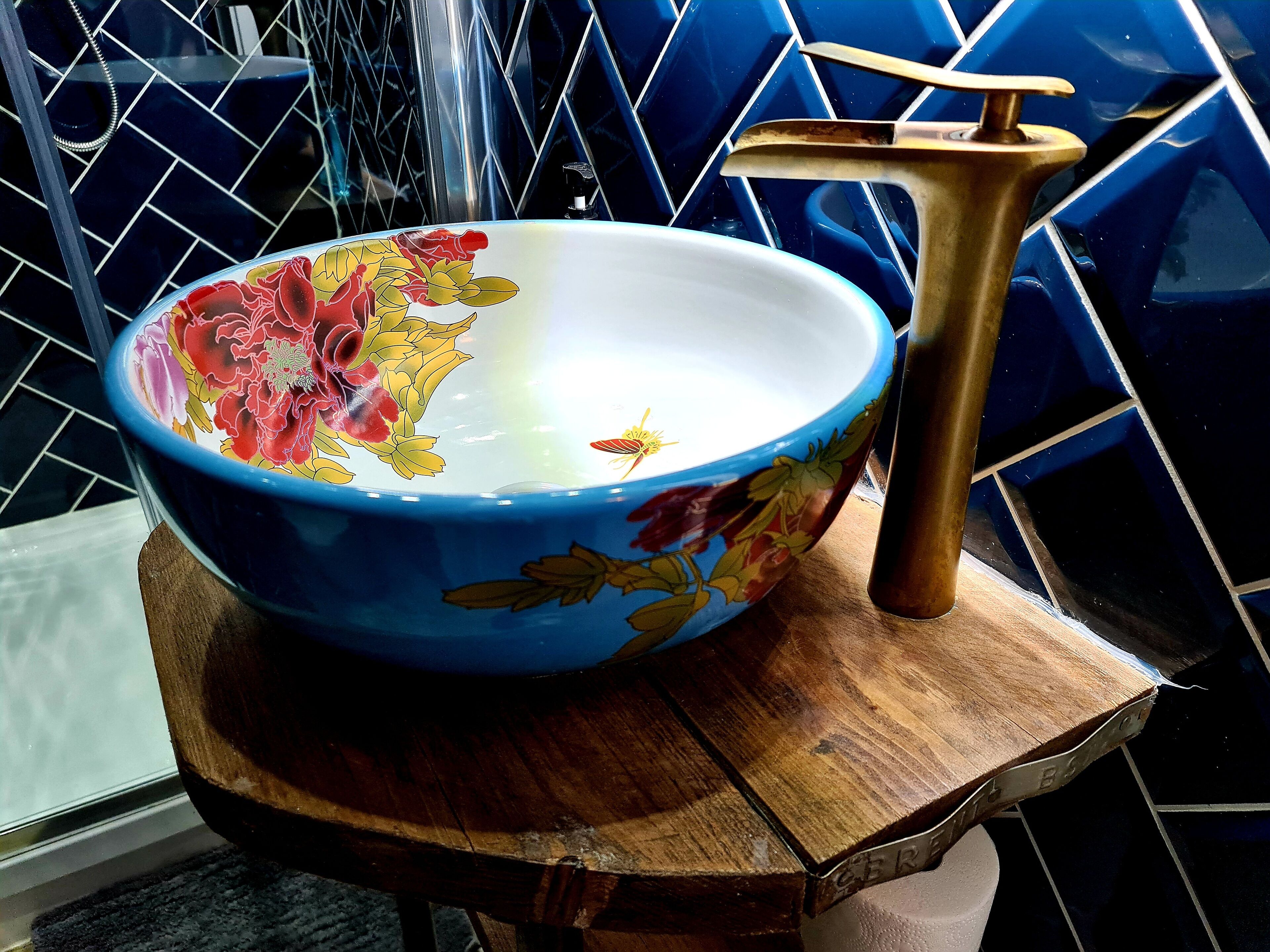 A large decorative bowl with floral patterns on a wooden stand.