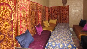 Een kamer met twee bedden, elk voorzien van beddengoed en kussens met een patroon. De muren zijn versierd met ingewikkelde, decoratieve motieven.