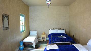 A bedroom with two beds, a window, a hanging lamp, and a small bedside table.