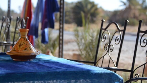 Een tafel met een blauw tafelkleed en een traditionele Marokkaanse tajine erop.