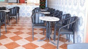 Een café met geruit vloerkleed, metalen stoelen en ronde tafels.