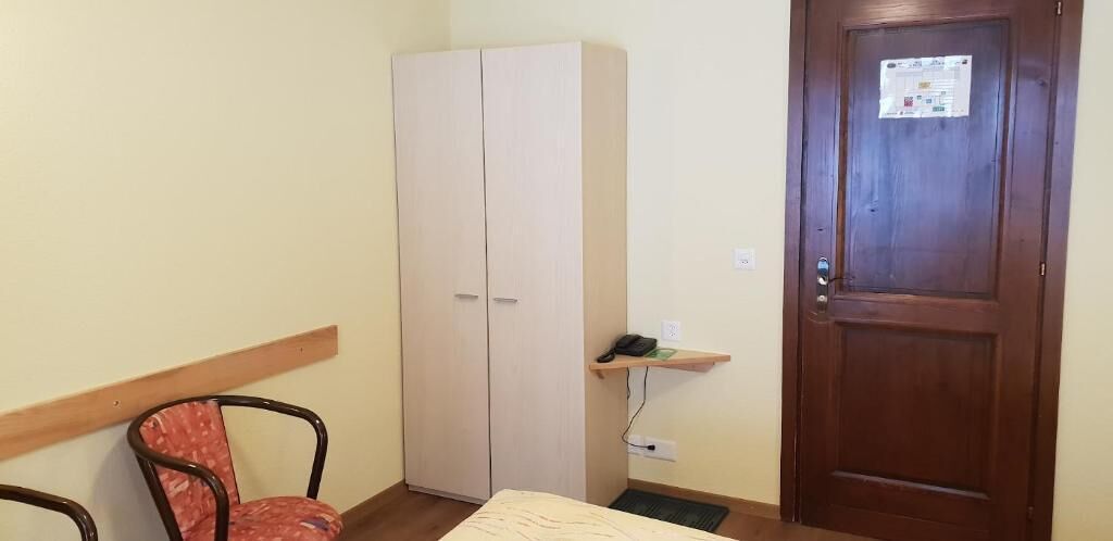 Una habitación con cama, una silla, un armario y una puerta.