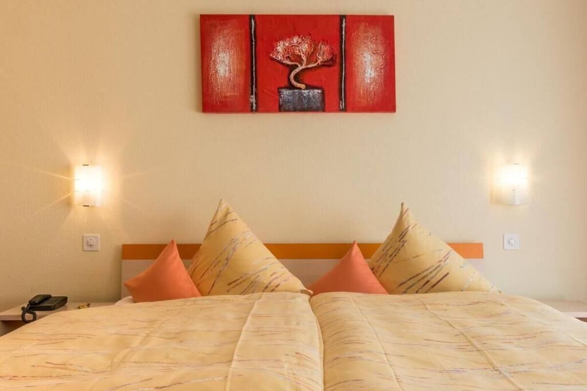 Una habitación de hotel con una cama, dos lámparas de noche y un cuadro en la pared.