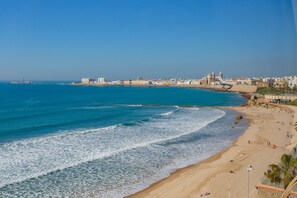 A coastal cityscape with a sandy beach, a rocky shoreline, and a clear blue sky. - GAVIOTA Family Home free parking by Cadiz4Rentals (Cádiz)