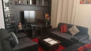 A modern living room with a flat-screen TV, dark sofas, a coffee table with shipping boxes, and a red rug. - Apartment Rosa elena b&b (A)Luz natural capacity 9 people in Cusco-Peru (Cusco)