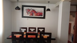 A dining area with a table and chairs, a framed painting on the wall, pendant lights, and a checkered floor. - Apartment Rosa elena b&b (A)Luz natural capacity 9 people in Cusco-Peru (Cusco)