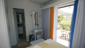 Une chambre d’hôtel avec un lit, une salle de bain, un petit lavabo et un balcon avec une chaise.