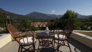 Une terrasse dotée de chaises et d’une table en osier, offrant une vue sur un paysage montagneux.