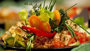 Une assiette de nourriture comprenant divers légumes et de la viande, agrémentée d’herbes aromatiques.